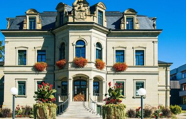Neues Schloss in Gaildorf mit Blumen geschmückten Fenstern und moderner Architektur im Hintergrund.