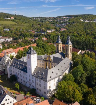 Luftaufnahme vom Residenzschloss Mergentheim. Man sieht den Schlosshof mit den Kirchtürmen, der Schlosspark im Hintergrund