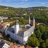 Luftaufnahme vom Residenzschloss Mergentheim. Man sieht den Schlosshof mit den Kirchtürmen, der Schlosspark im Hintergrund