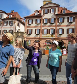 Blick auf eine Gruppe Menschen auf dem Bad Mergentheimer Marktplatz. Im Hintergrund sind die Zwillingshäuser zu sehen.