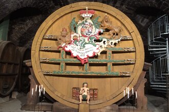 Im Museum steht ein großes altes Weinfass, davor sind Kerzen angezündet