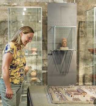 Eine Frau steht vor einer Vitrine mit römischen Funden