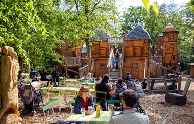Der Abenteuerspielplatz "Koboldburg" im Hintergrund. Eltern nebenan im Biergarten.