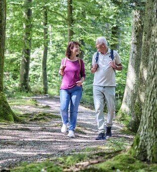Ein Paar unternimmt eine Wanderung durch den Wald. Sie schauen sich an und lachen.
