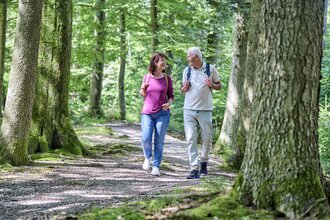 Ein Paar unternimmt eine Wanderung durch den Wald. Sie schauen sich an und lachen.