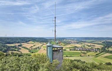 Weiter Blick über die Baumspitzen in die Hohenloher Ebene mit dem Aussichtsturm auf dem Einkorn bei Schwäbisch Hall im Vordergrund.