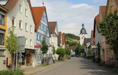 Entlang der Straße reihen sich Häuser und eine Kirche ist am Ende.