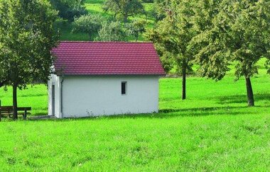 Die Kapelle liegt idyllisch inmitten einer grünen Wiese und Bäumen