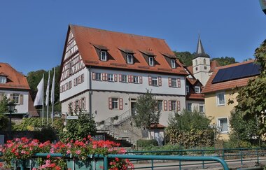 Ein altes Fachwerkgebäude und eine Kirche sind von einer Brücke aus zu sehen