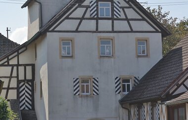 Das weiße Rundtor hat oben am Giebel Fachwerk