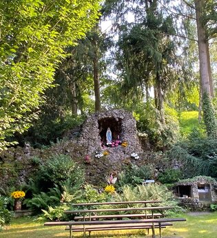 Die Grotte ist ein Freiluftort mit Bäumen und Bänken