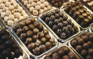 Auf unterschiedlichen kleinen Metalltablets liegen verschiedene Pralinen- und Schokoladenvariationen